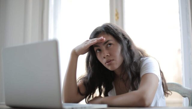 annoyed woman looking away while using laptop