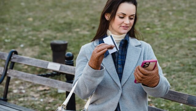 woman shopping online using phone while holding credit card
