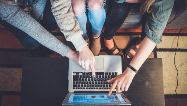 people pointing at laptop